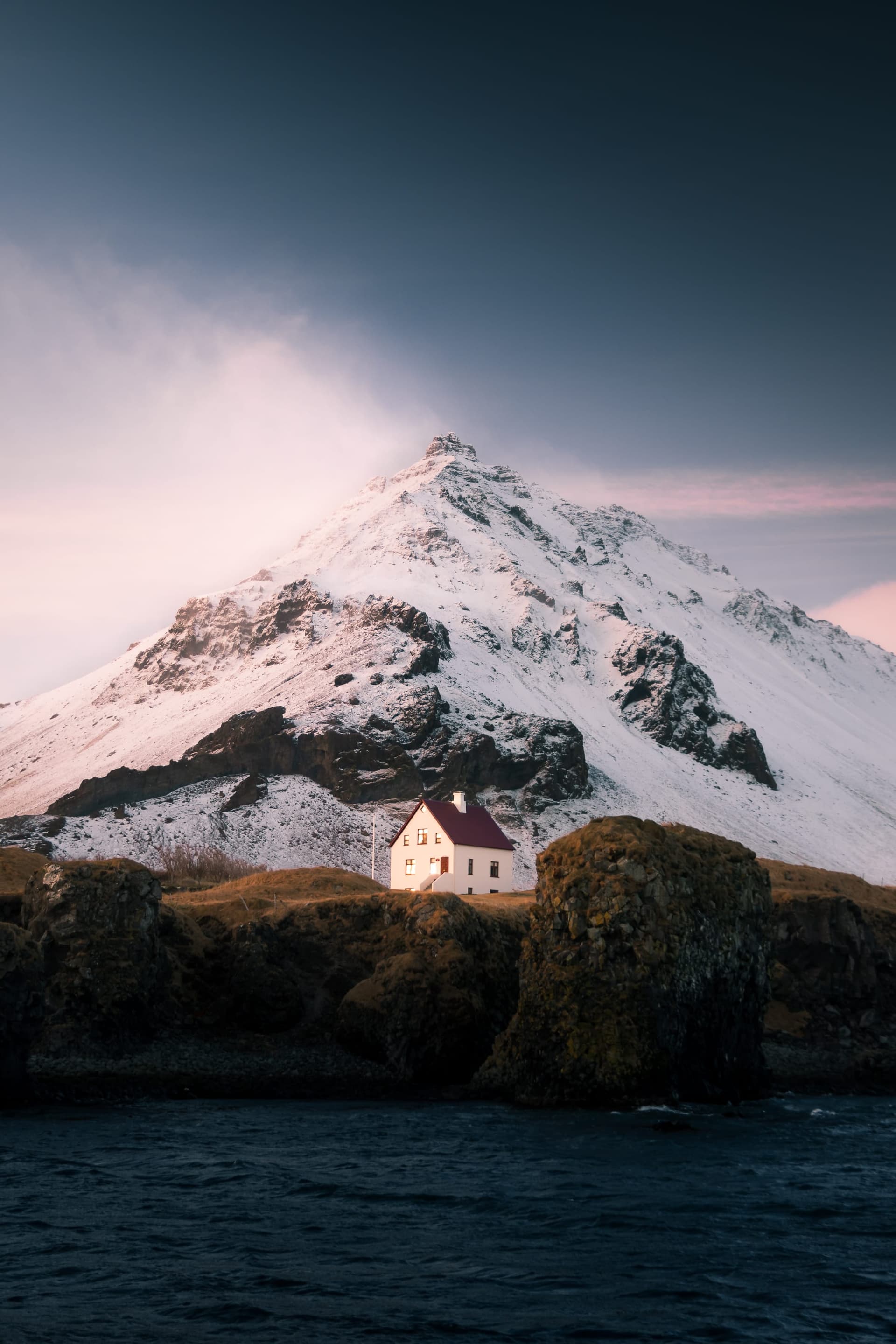 A solitary house beneath a steep Icelandic mountain