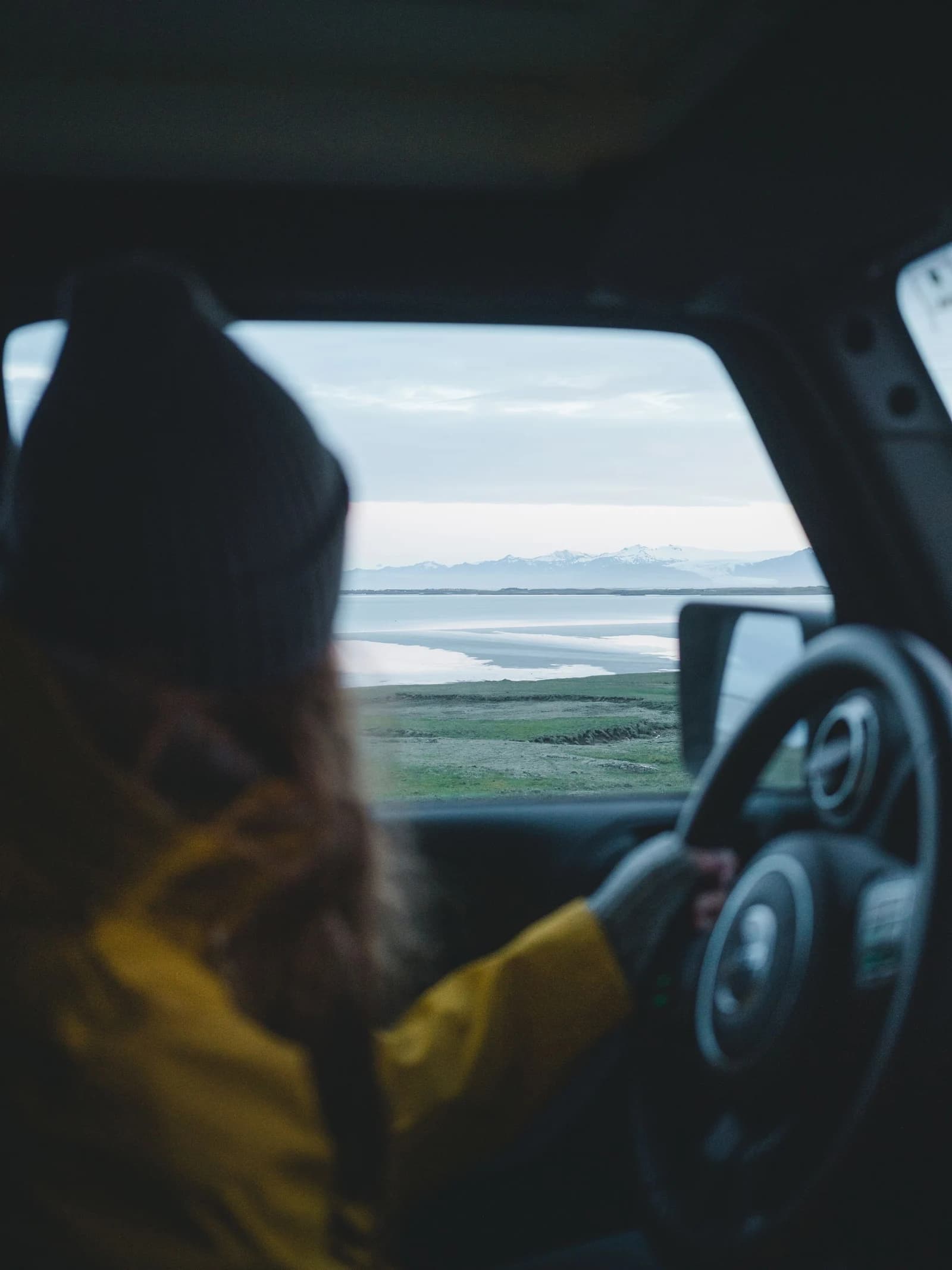 A traveller at the wheel looking out towards Iceland’s coastline