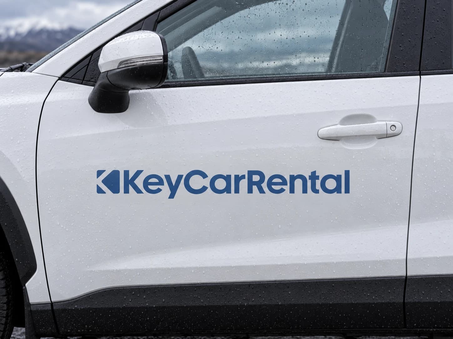 Close view of the Key Car Rental door decal with rain on the window and mirror