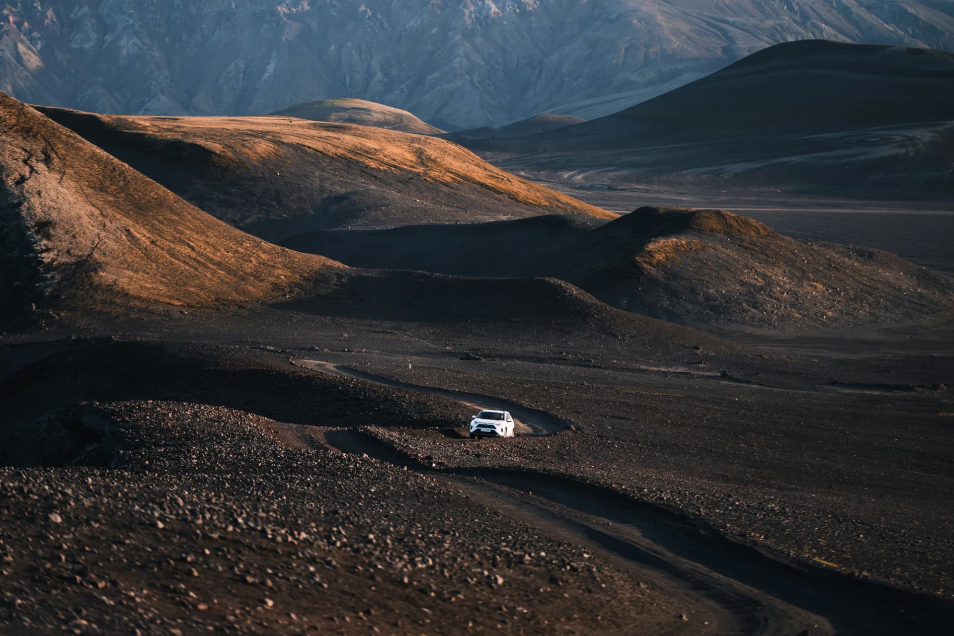 A small white vehicle in a wide Icelandic highland landscape