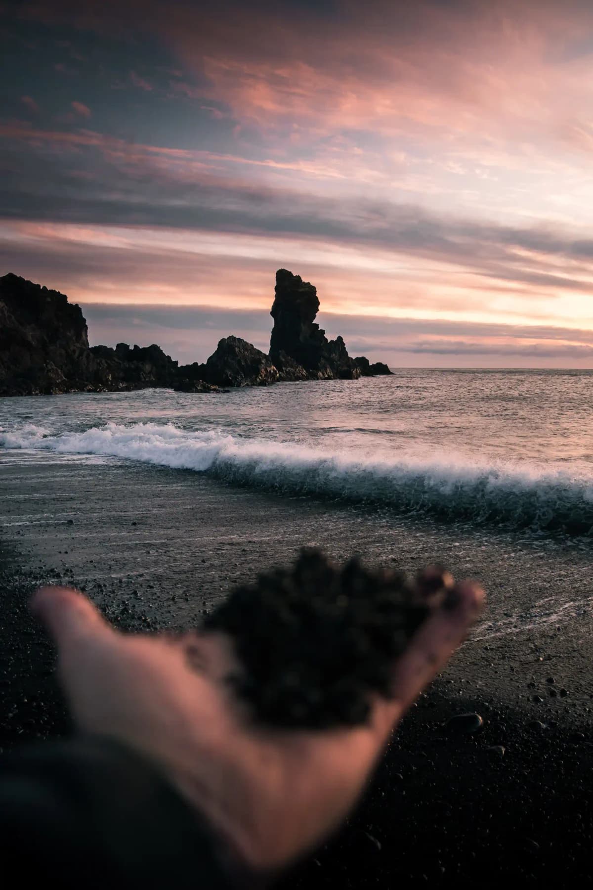 Dark Icelandic coastline and sea stacks beneath a softly colored evening sky