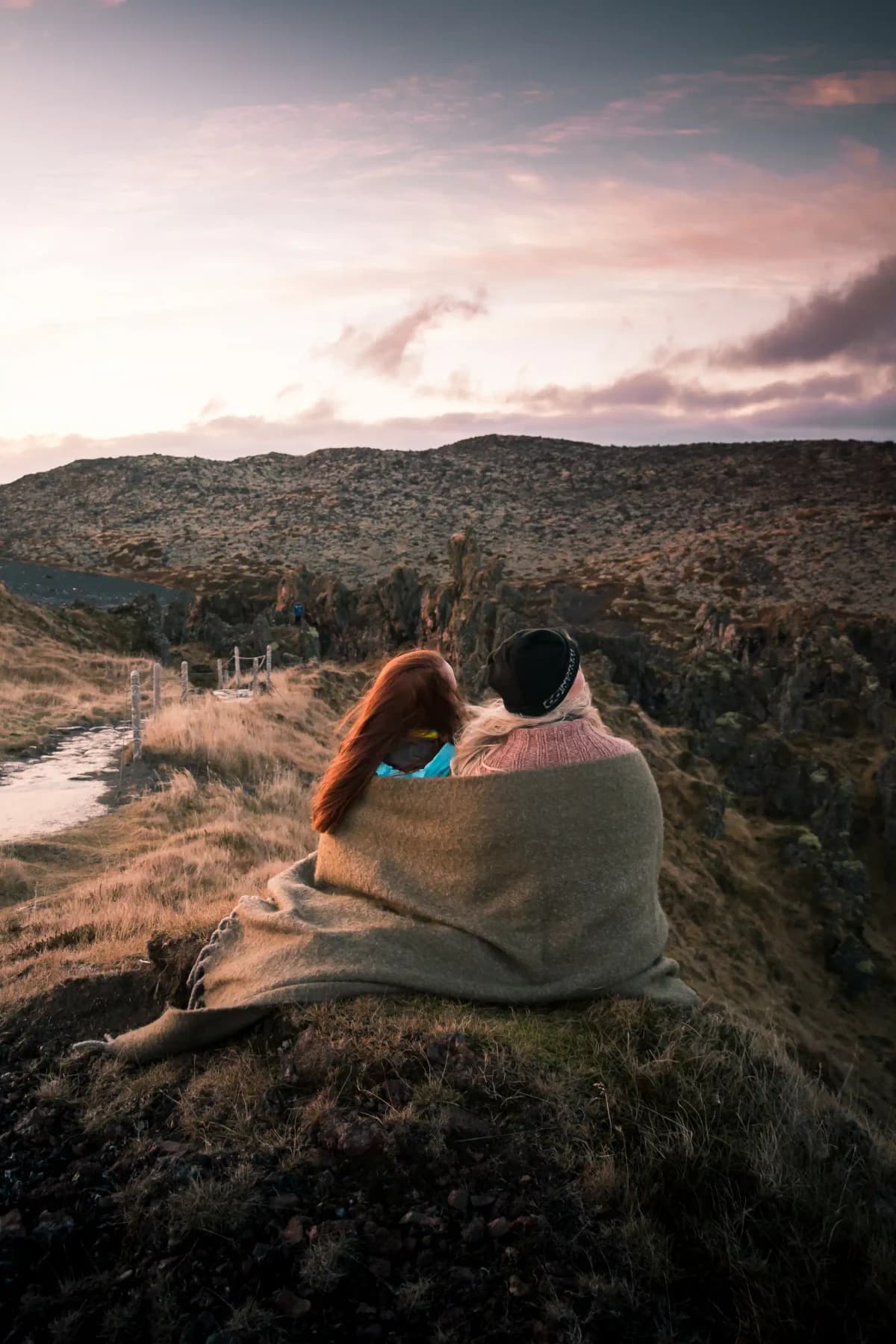 Two travellers sitting together in an Icelandic landscape at sunset