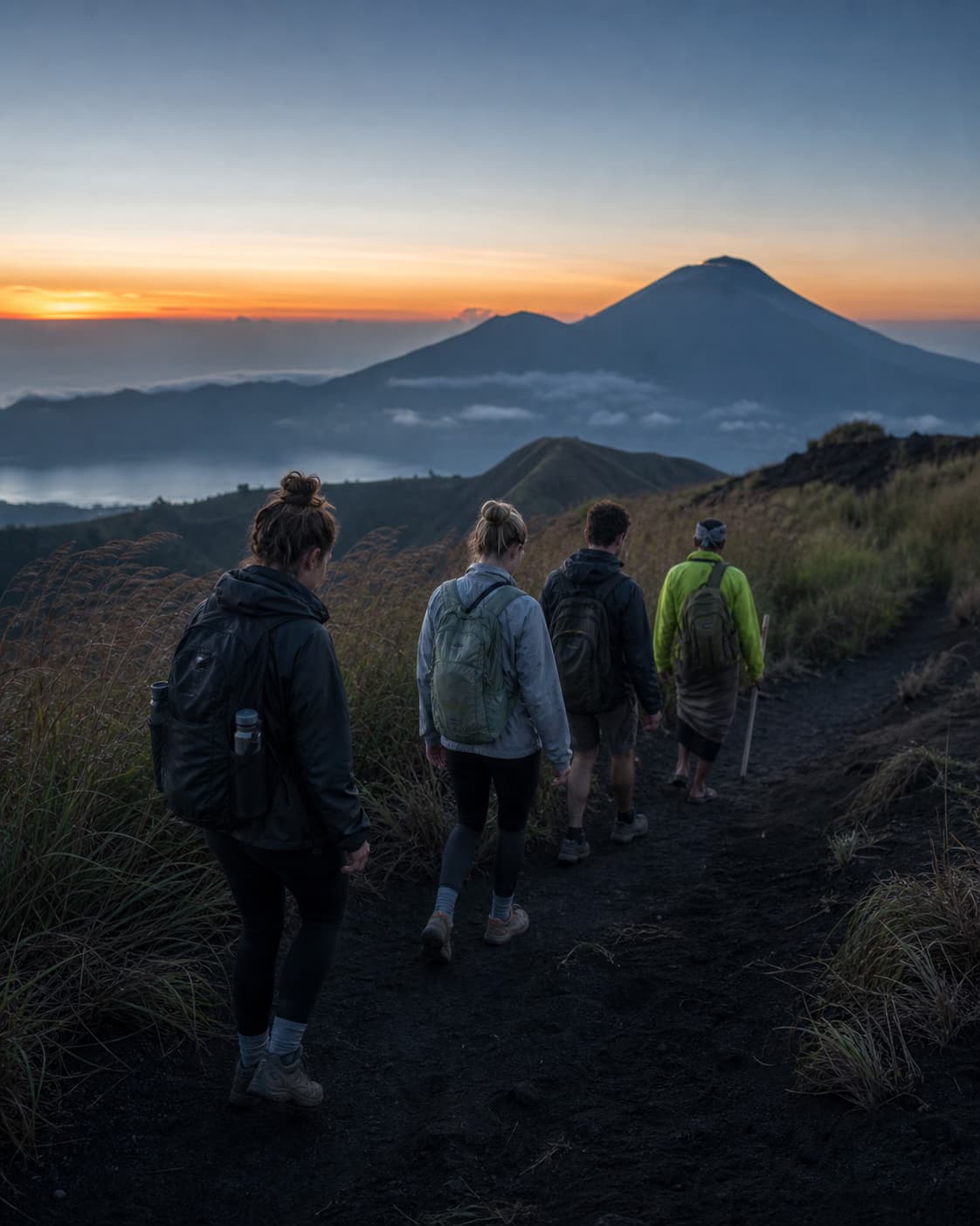Art-directed concept of a local guide leading a small group along a Bali volcanic trail before sunrise
